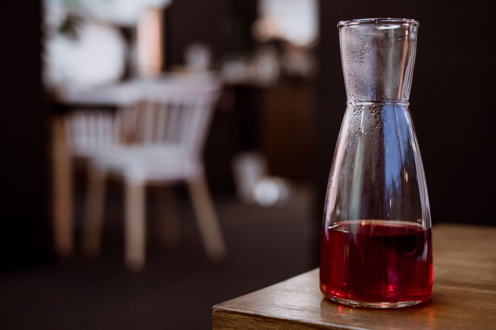 Glas rode vermout met ijs en een schil sinaasappel op een wit tafelblad