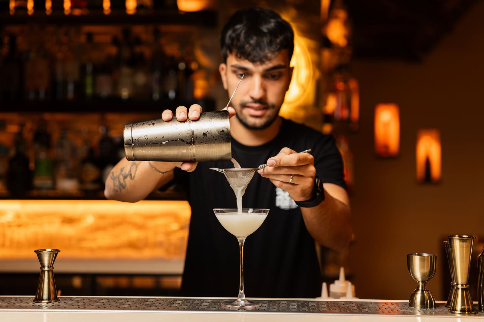 Bartender achter de bar die een cocktail schenkt voor gasten aan de toog