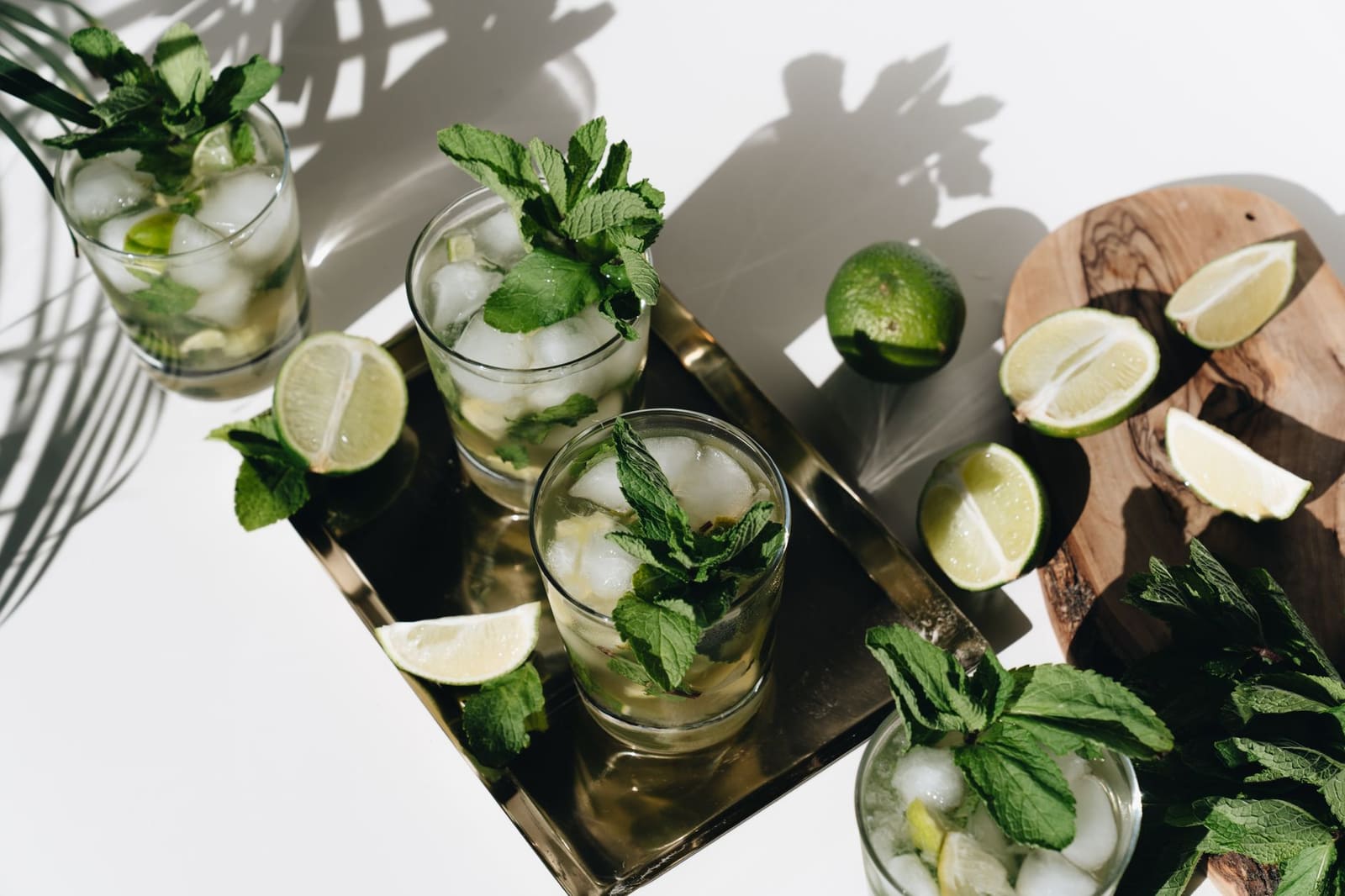 Mojito in een hoog glas met verse munt, limoen en ijs op tafel.