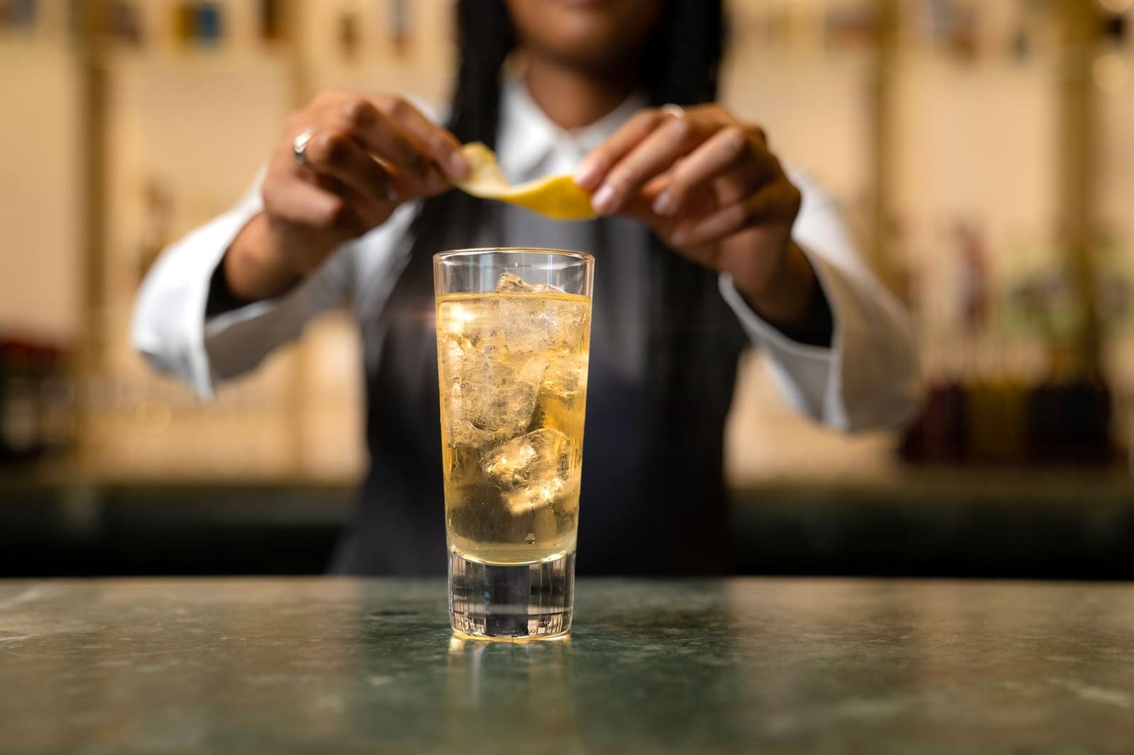 Bartender roert een cocktail in een mixglas met ijs op een donkere bar