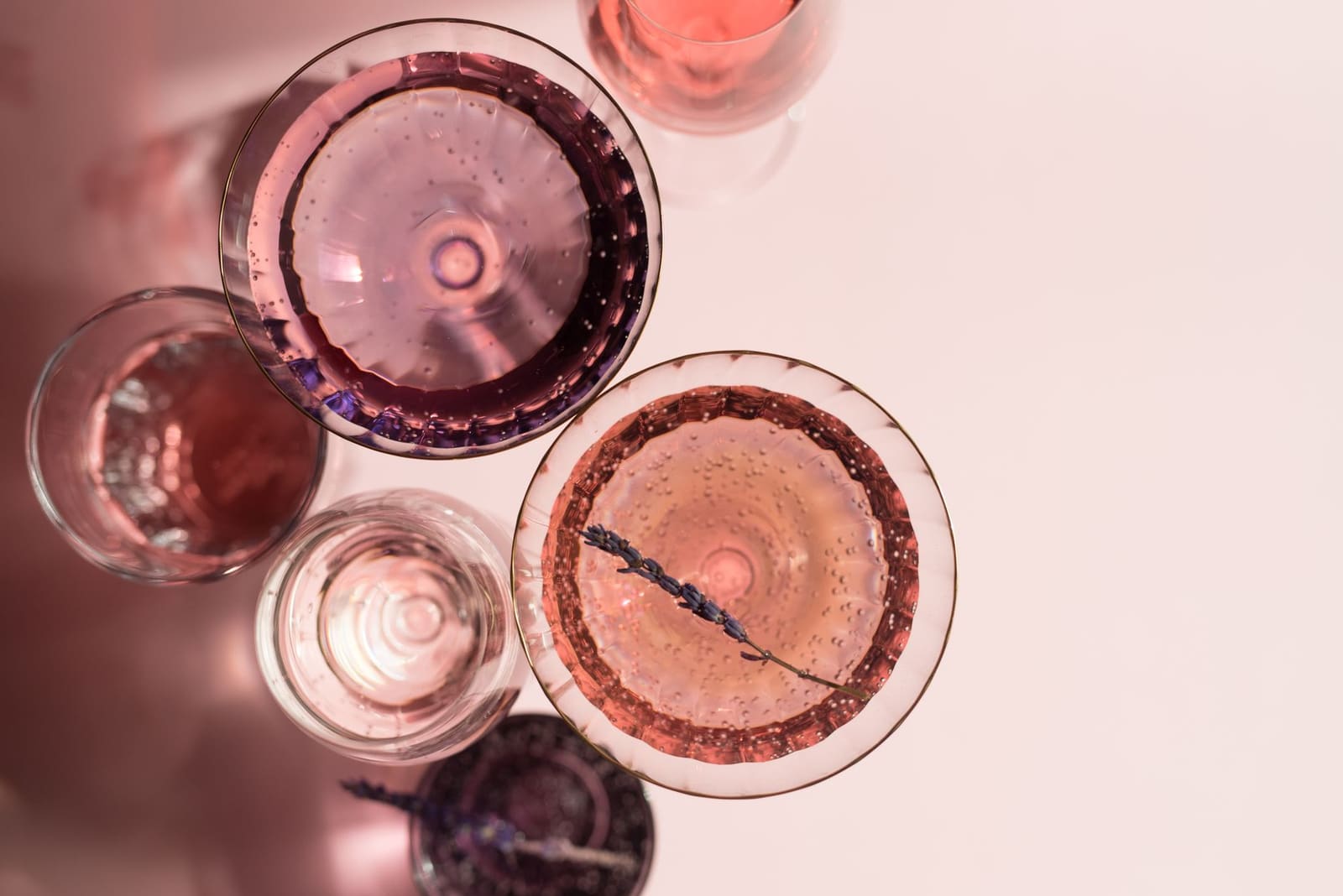 Rozékleurige cocktails in glazen van bovenaf gefotografeerd met lavendeltakje als garnering.