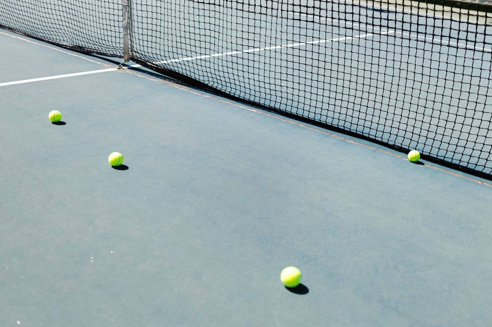 Gele tennisballen liggen op de lijnen van een tennisbaan
