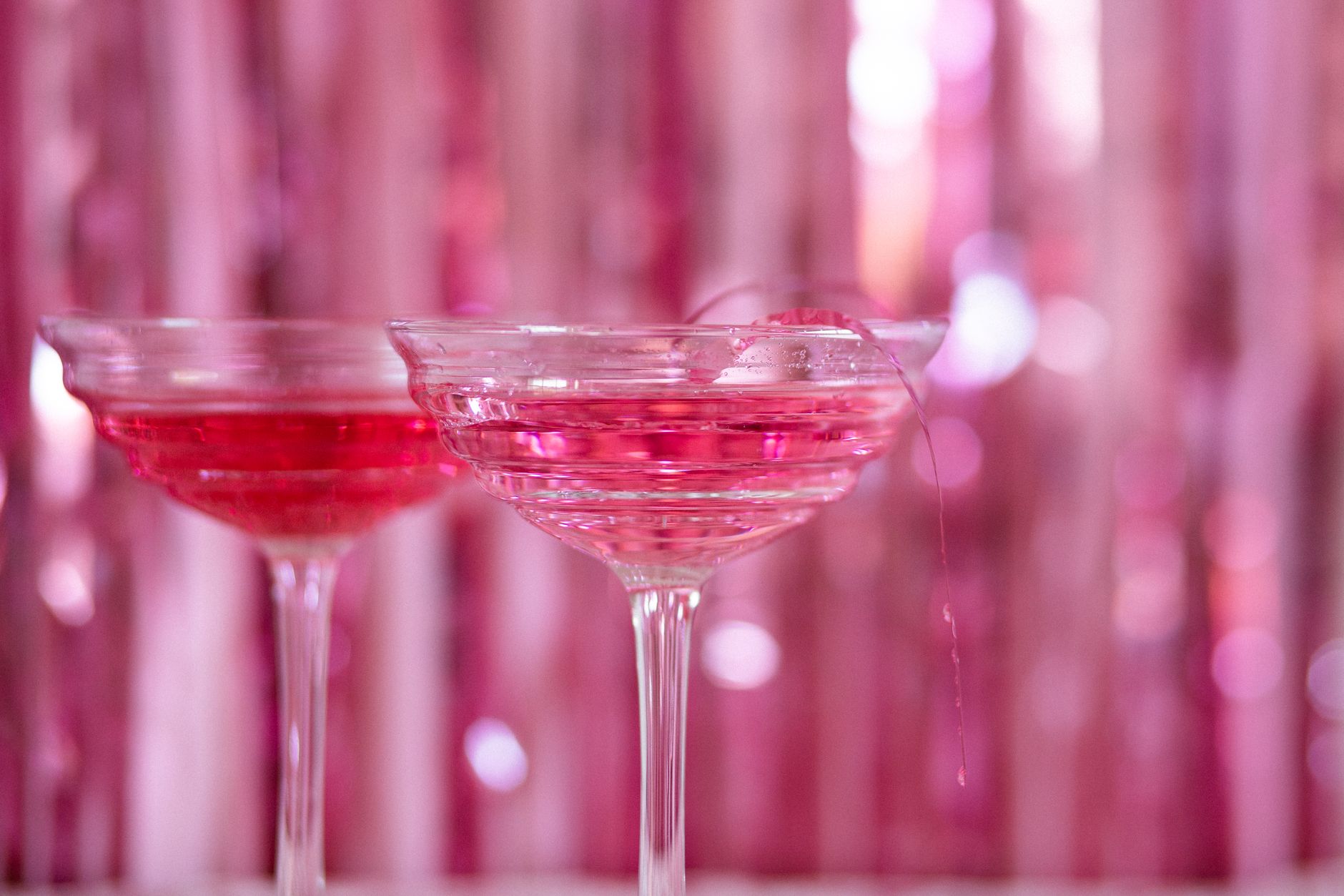 Roze Honey Deuce cocktail in glas met drie meloenballetjes als garnish