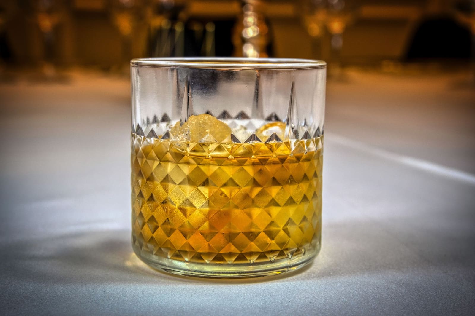 Glas Ierse whiskey met een enkel ijsklontje op een houten bar