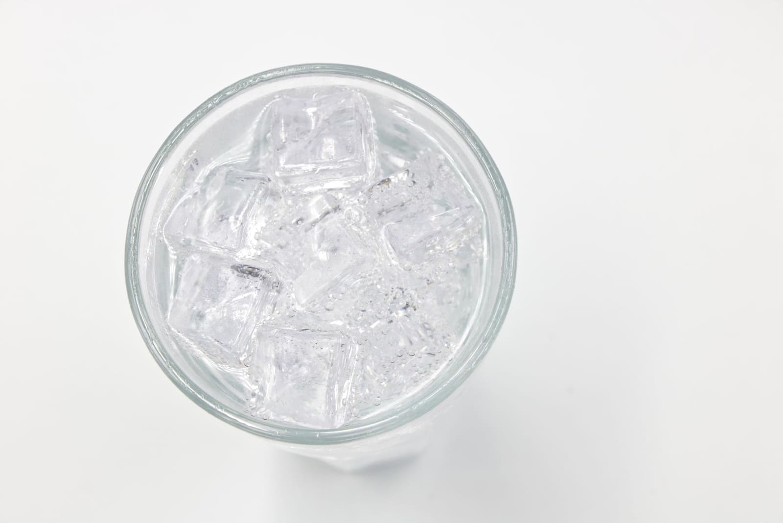 Grote heldere ijsblokken in een kristallen tumbler met een schil van limoen