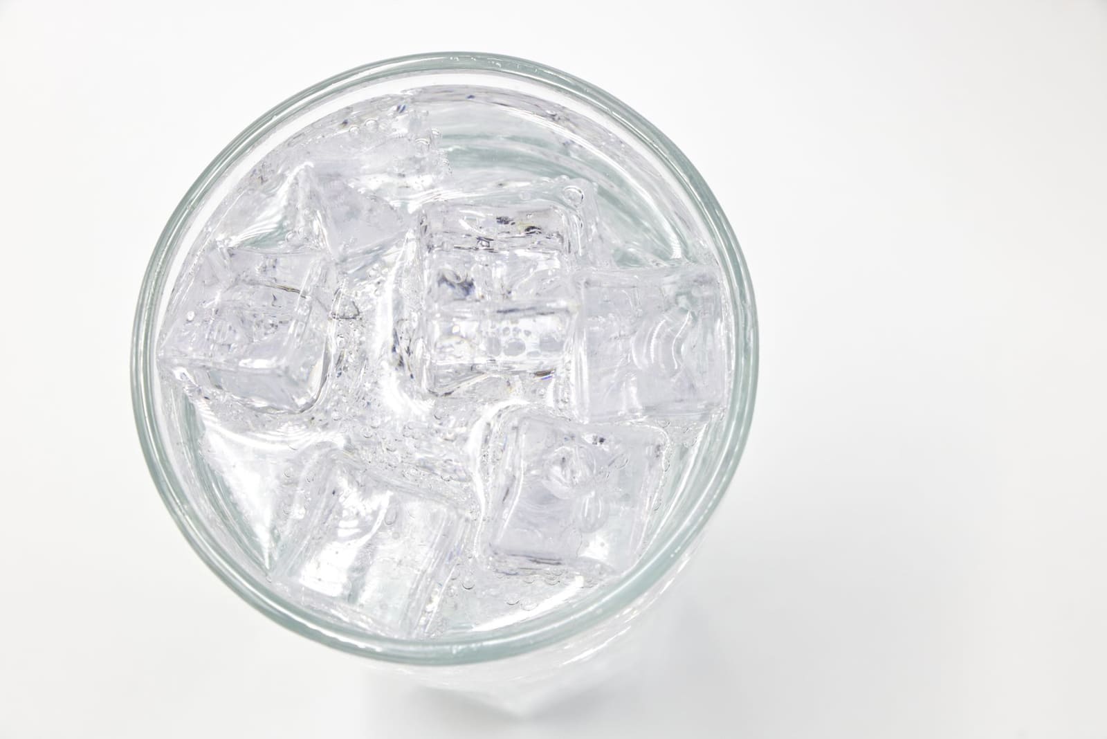 Een gin-tonic in een hoog glas met koud ijs en een schil citroen op een bar.