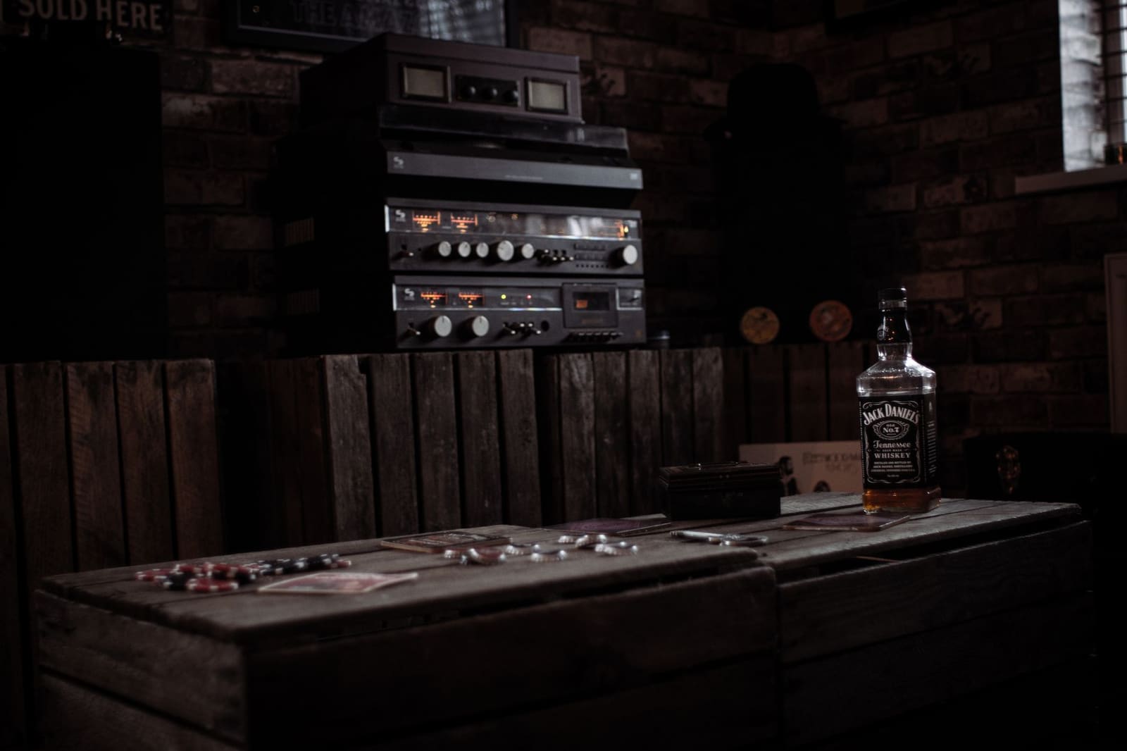 Fles Jack Daniel's whiskey op houten kist in sfeervol verlichte retro bar/zolderkamer.