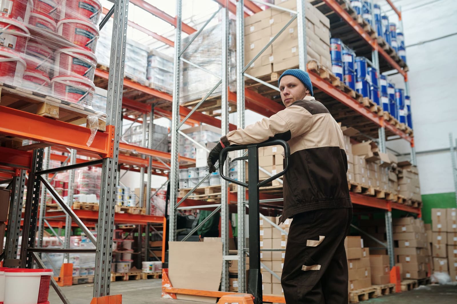 Een medewerker controleert pallets met flessen in een groot distributiemagazijn