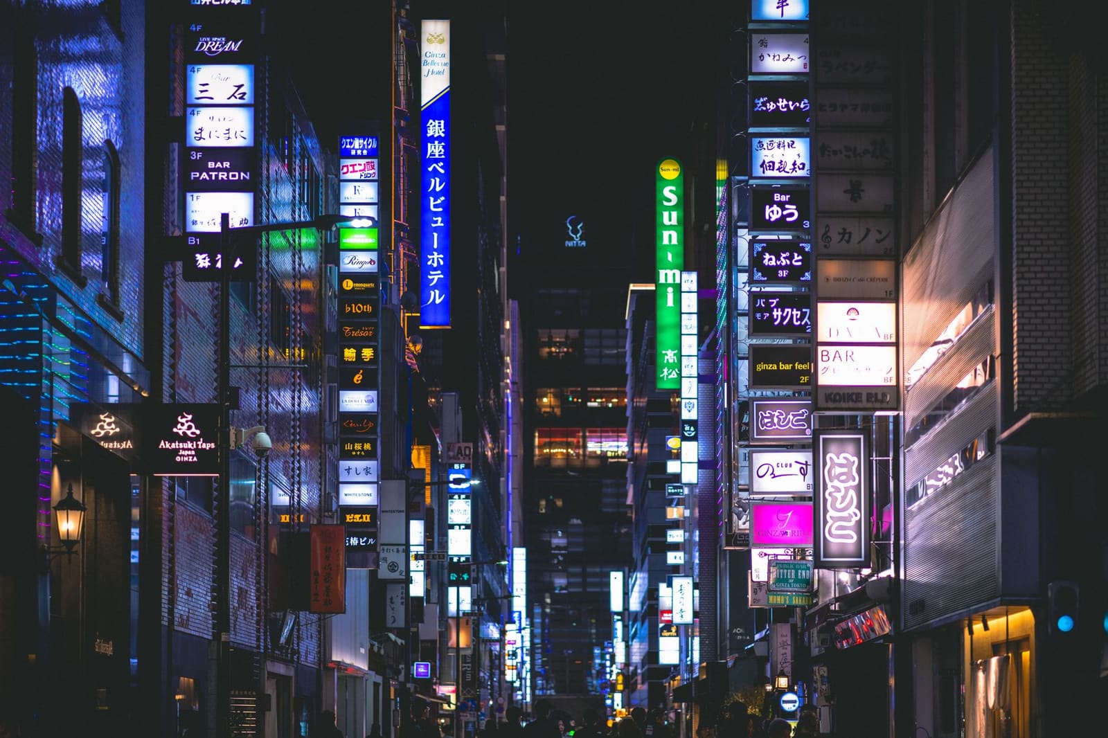 Drukke nachtelijke straat in Japan met opgestapelde neonreclames en bar- en restaurantborden.