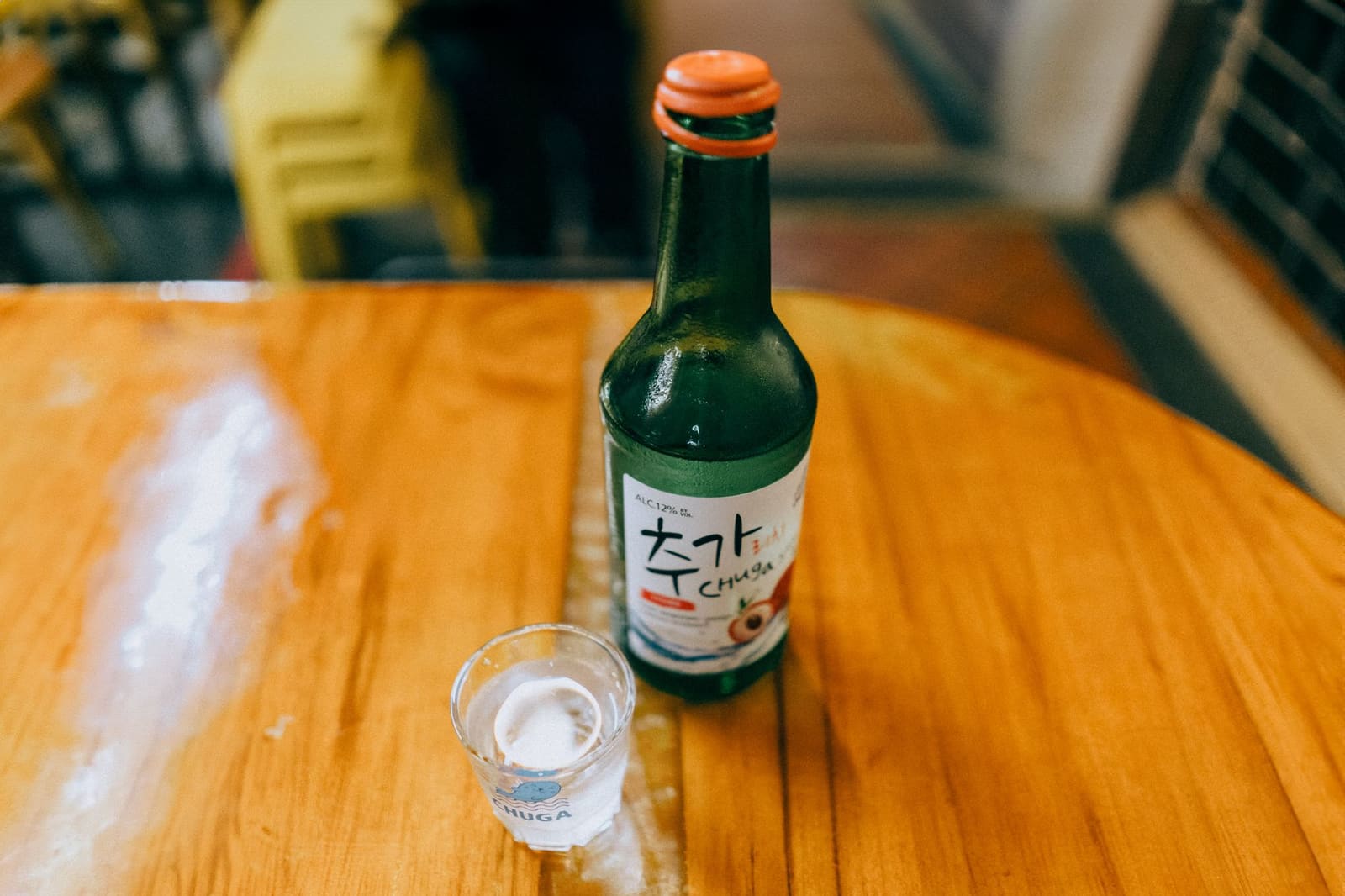 Iemand schenkt heldere soju uit een fles in een klein glaasje