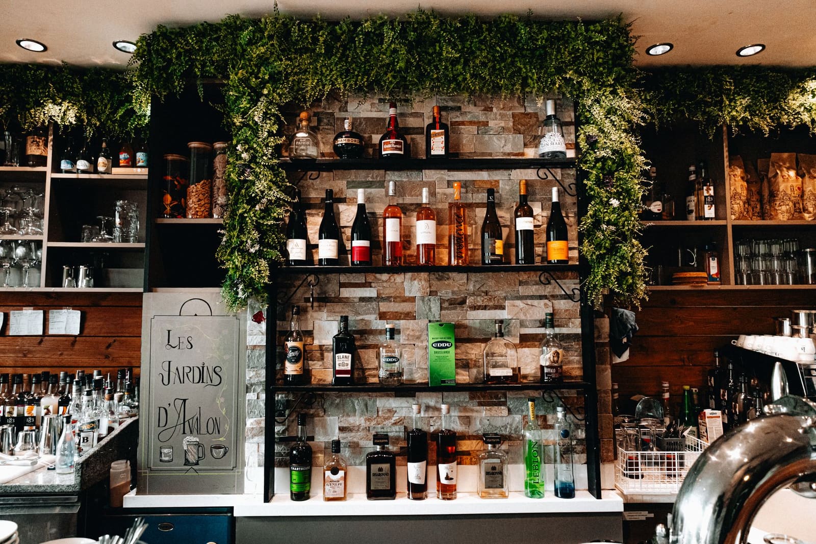Flessen sterkedrank en wijn op schappen tegen een stenen muur in een bar.