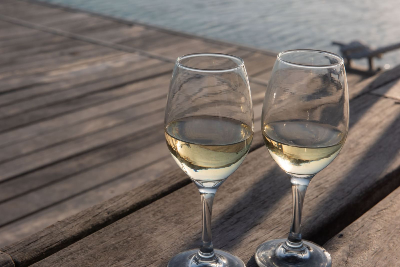 Glas koele witte wijn op een houten tafel buiten