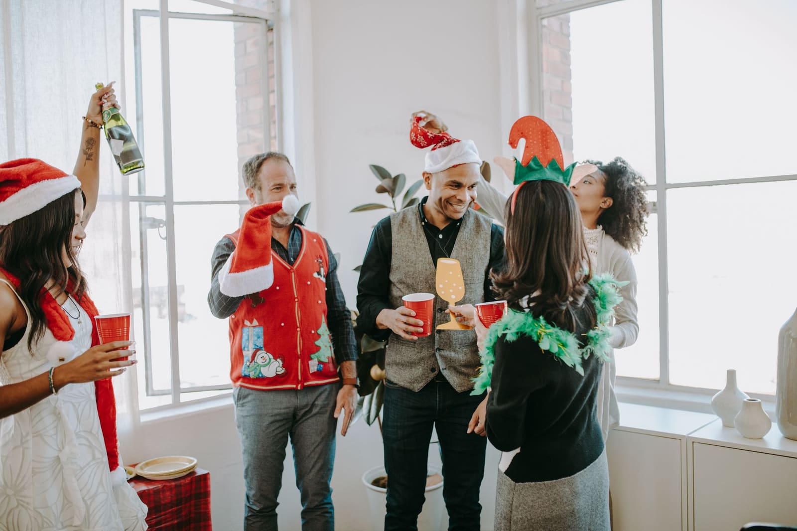 Collega's met kerstmutsen proosten met een drankje op een kerstborrel op kantoor