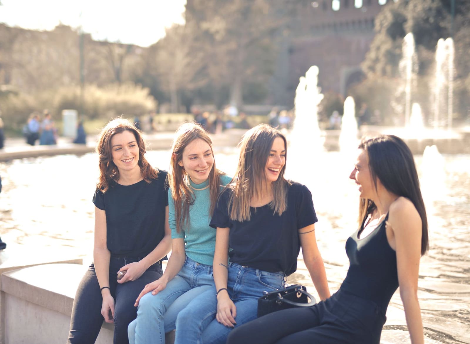 Vrienden lachen samen op een terras met glazen in hun hand.