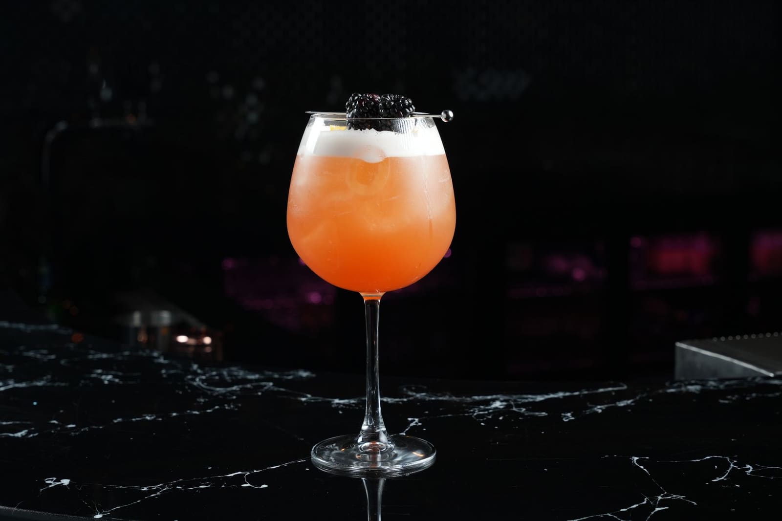 Een donkere cocktail in een glas, met een garnish op de rand van het glas