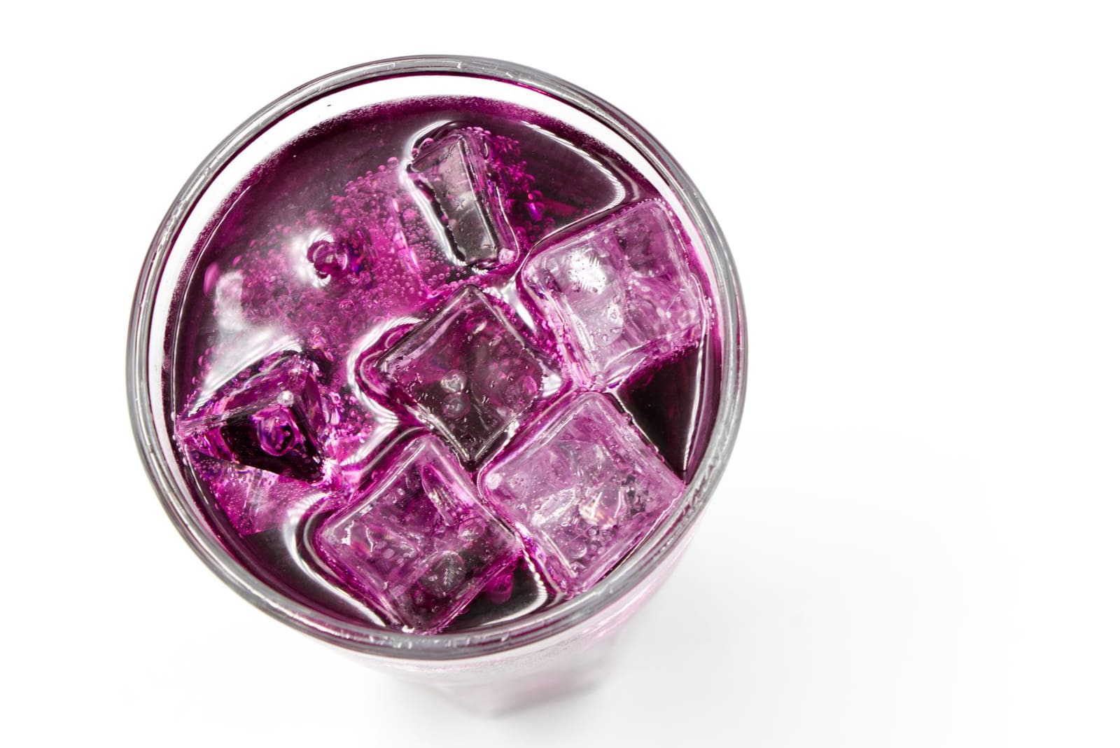 IJsblokjes drijven in paarse cocktail, bekeken van bovenaf in glas.