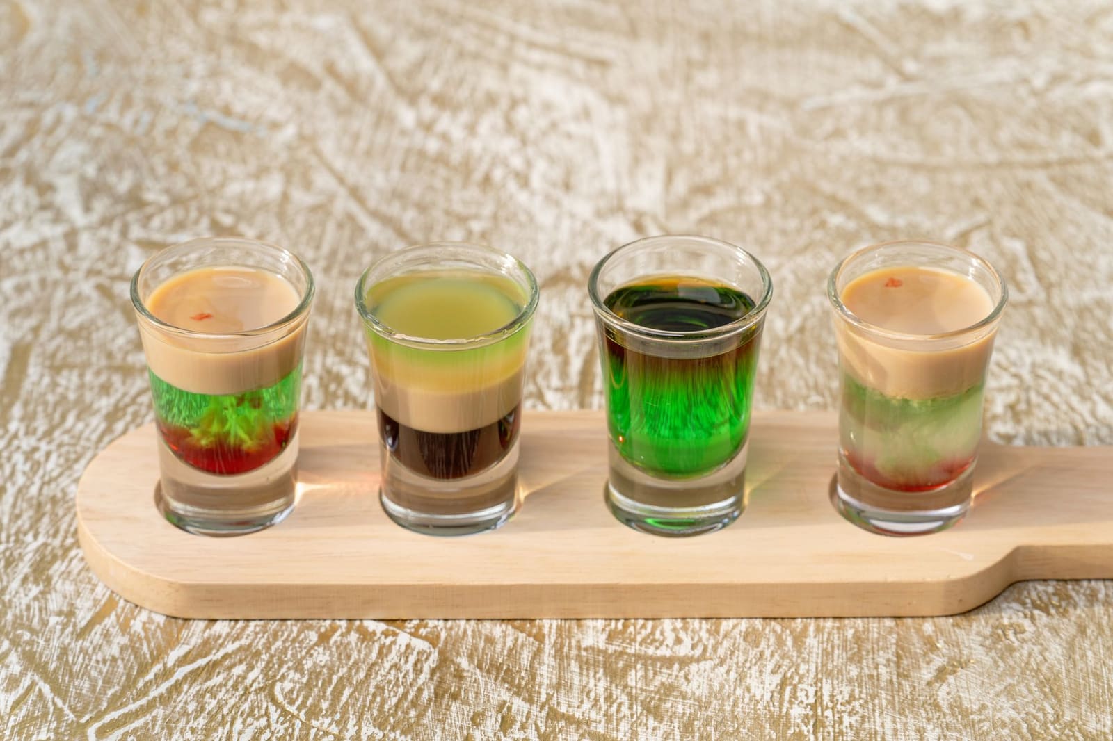 Rij gekleurde cocktails met garnering op een bar