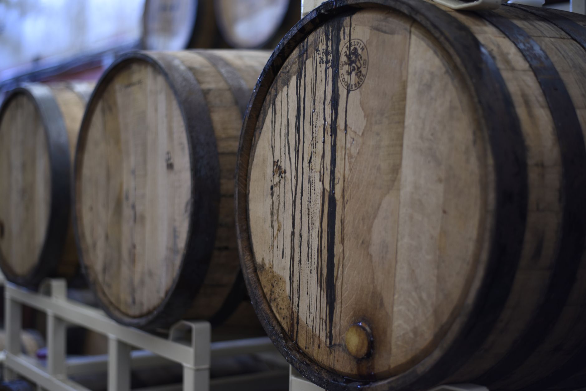 Rijen eikenhouten bourbonvaten in een koele kelder tijdens rijping van bourbon whiskey