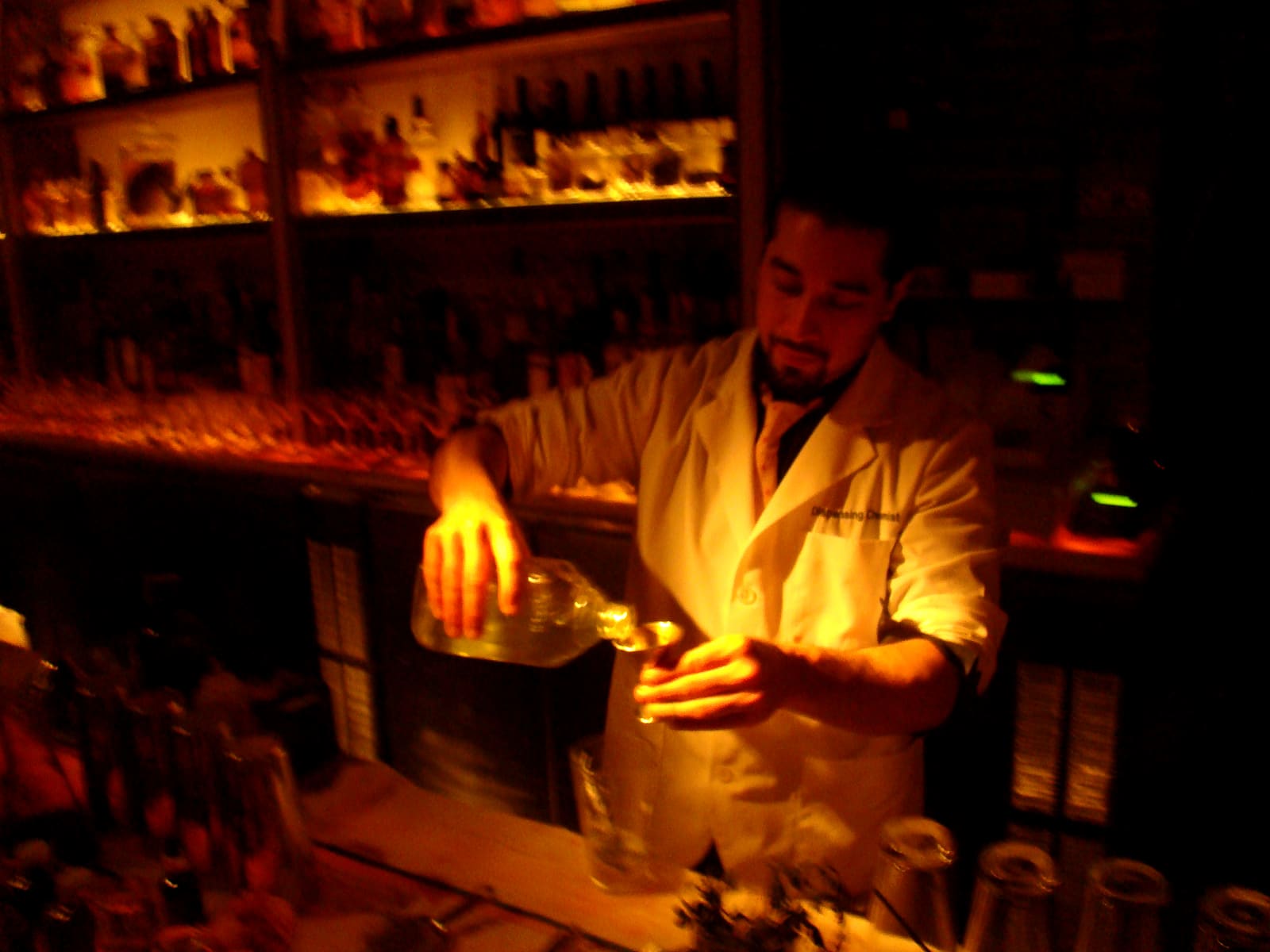 Bartender schenkt zorgvuldig een cocktail in een klein glaasje achter de bar