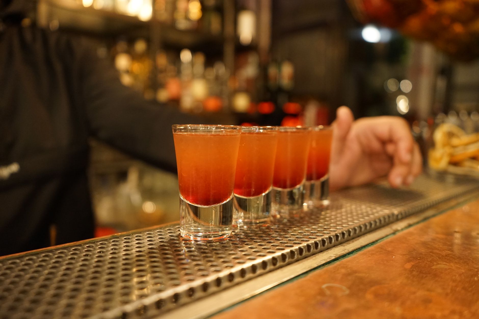 Kleine gegraveerde cordial-glaasjes met mini-cocktails op een bar, voorbeeld van de little beverages trend