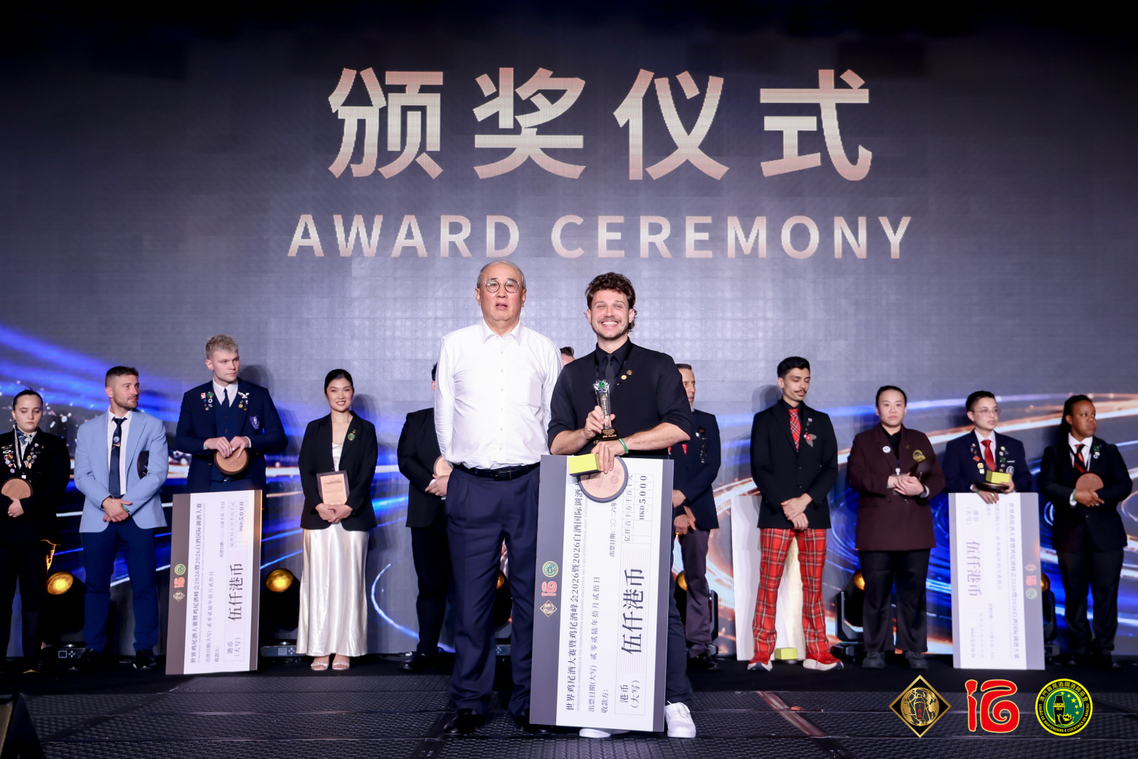 Prijsuitreiking op het podium van het World Cocktail Championship 2026 in Macau, met de deelnemers op een rij