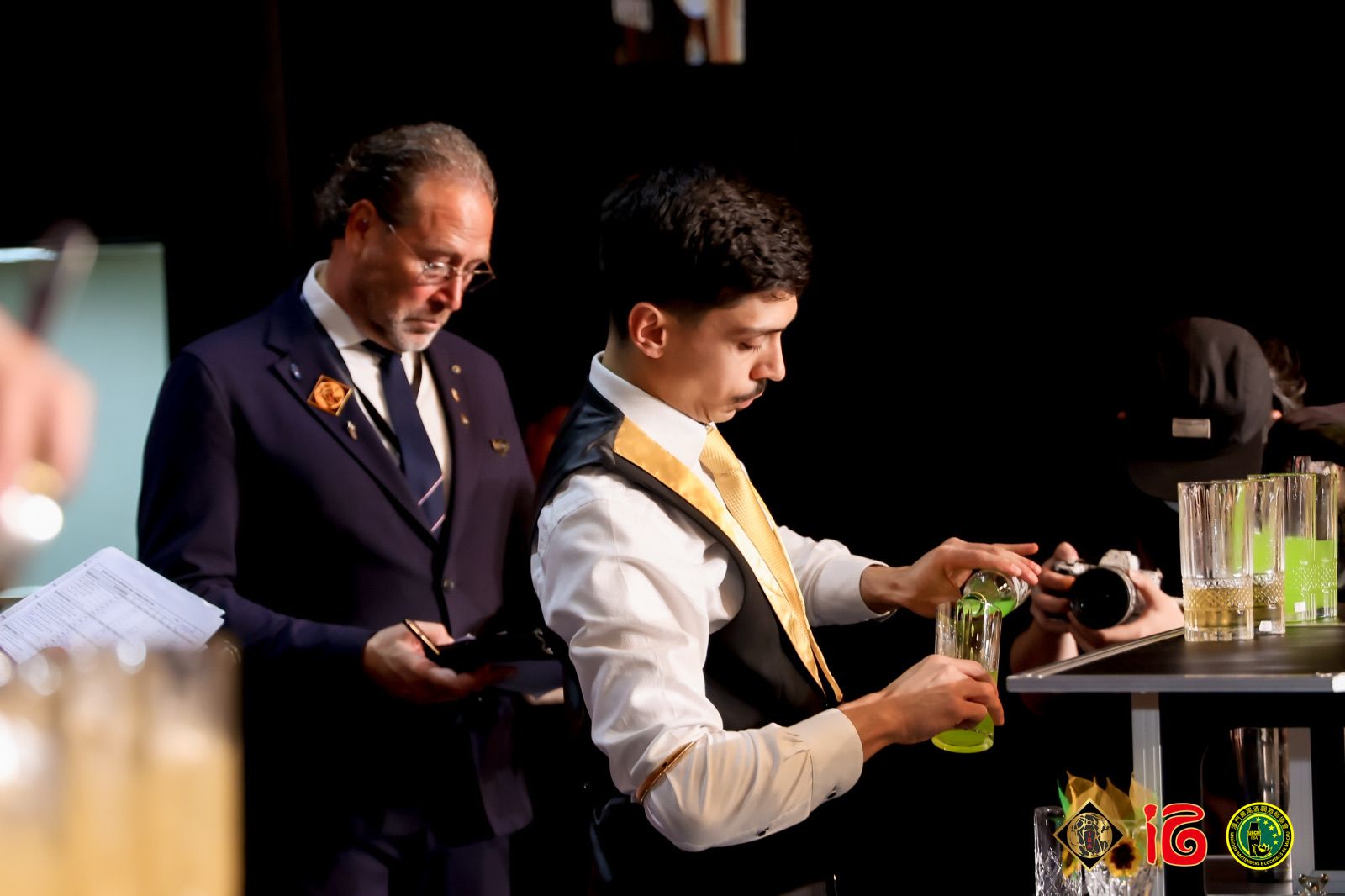 Jurylid kijkt mee terwijl een deelnemer een groene cocktail inschenkt