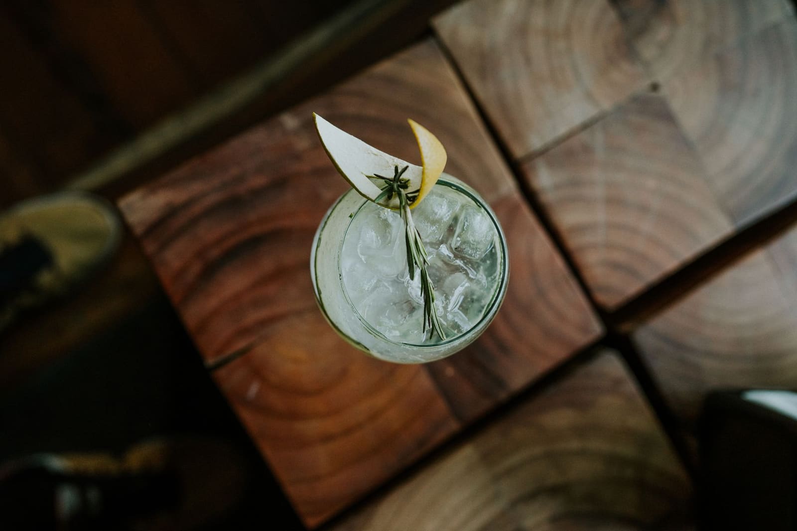 Een gin-cocktail in een glas met een schil citroen als garnish op de bar.