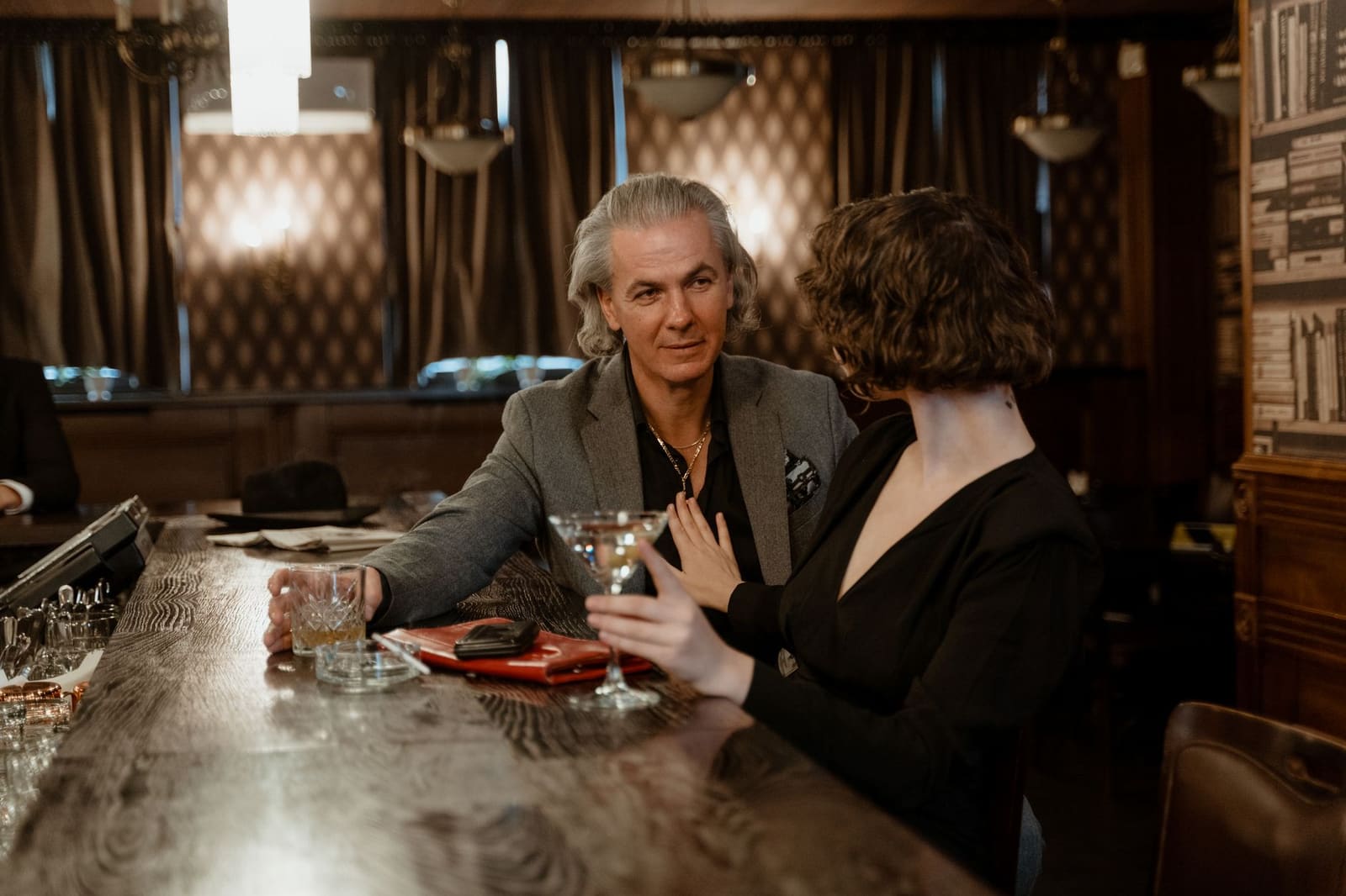 Een sfeervolle cocktailbar met gedimd licht, flessen op de achterwand en krukken aan de toog.