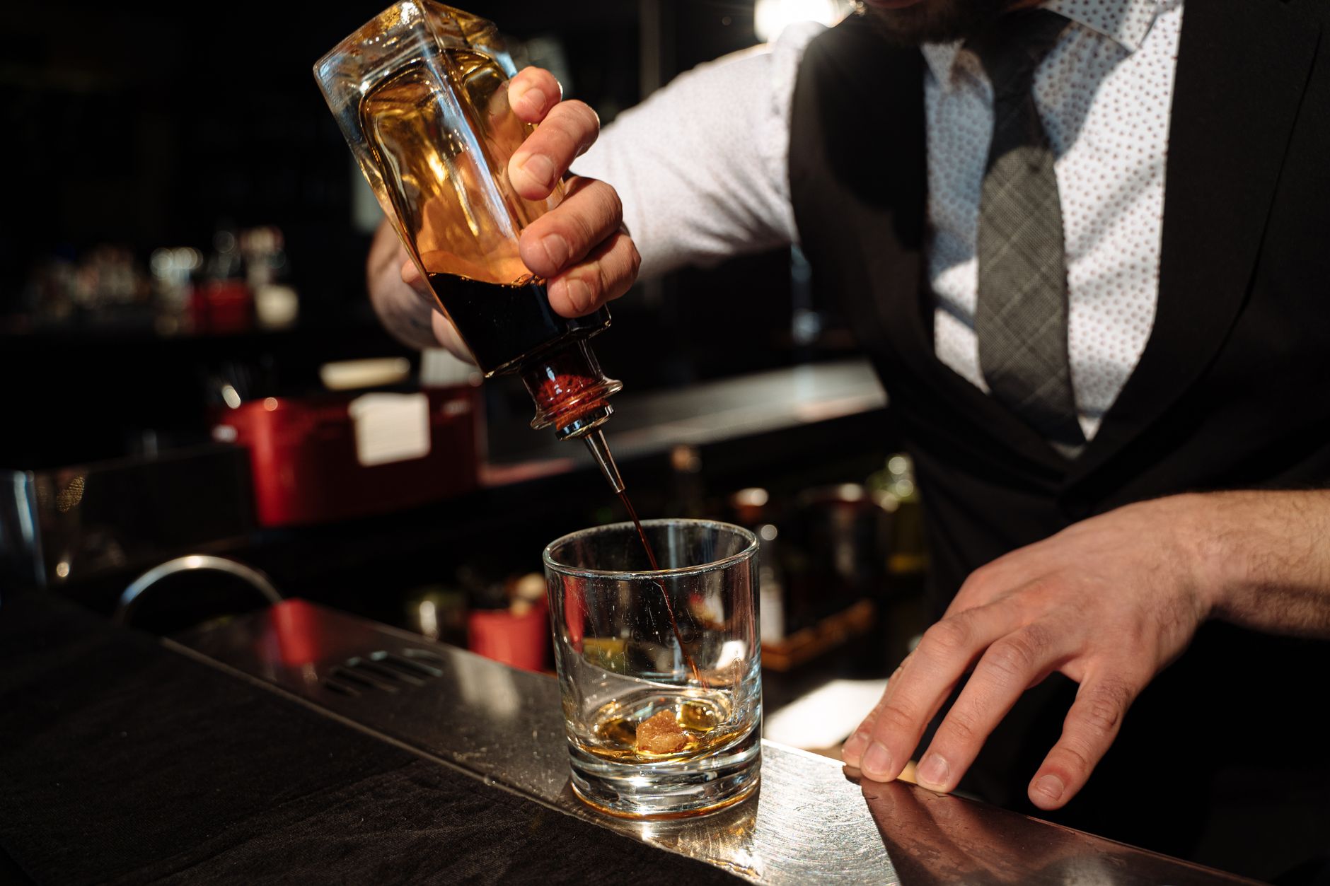 Een amberkleurige whiskeycocktail met ijsblok en garnering, klaargezet op een houten bar