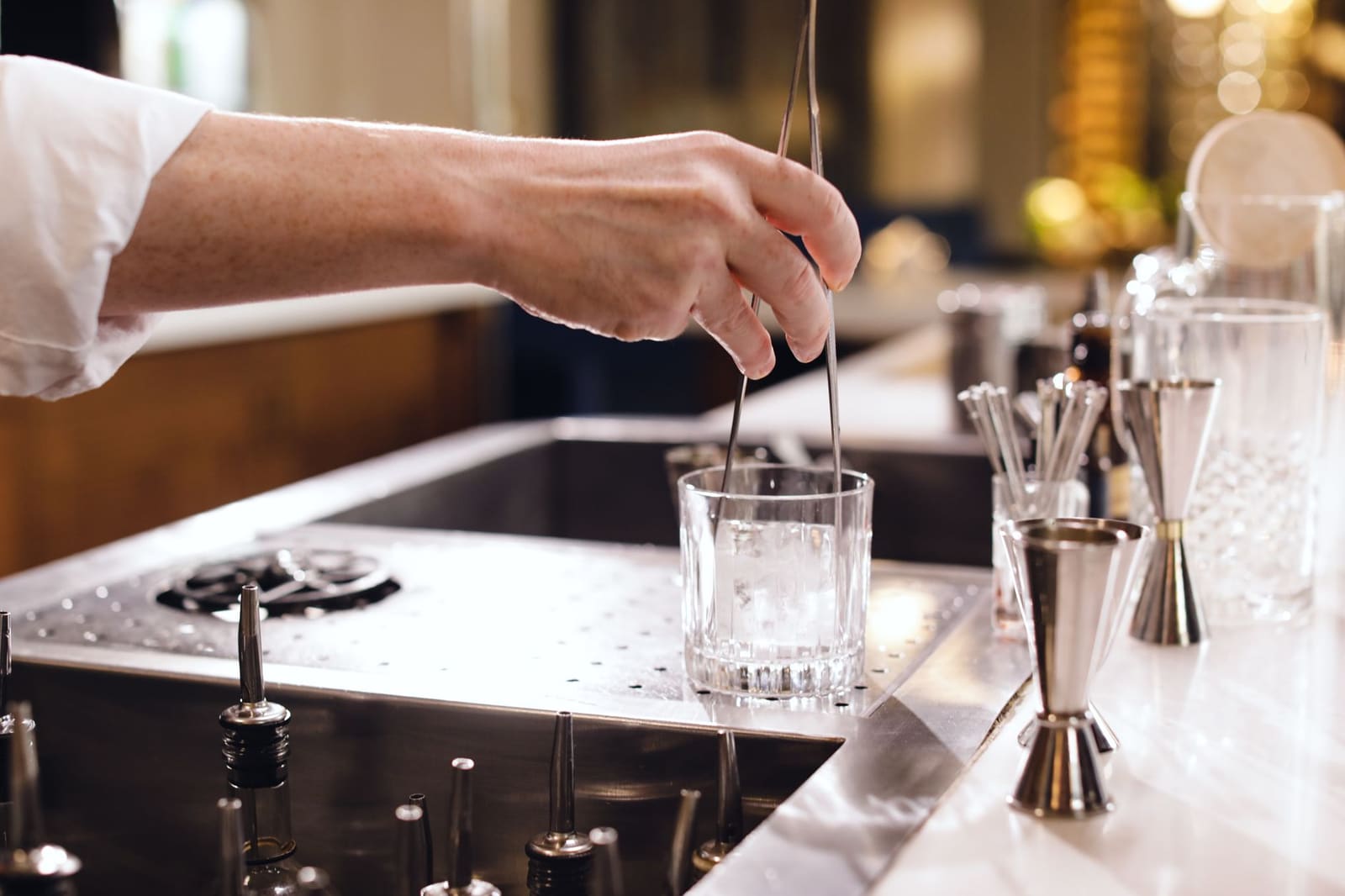 Bartender roert een cocktail met ijs in een mengglas