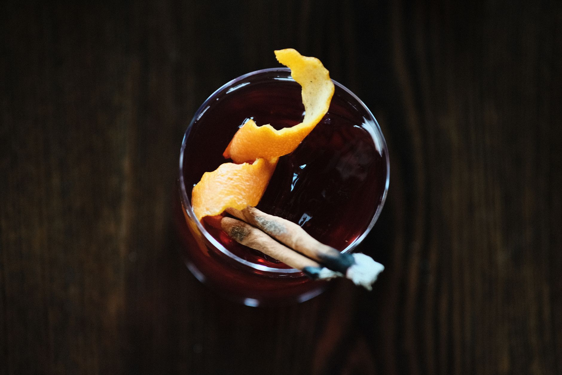 Negroni cocktail met ijsblokken en sinaasappelschil in een laag glas op de bar