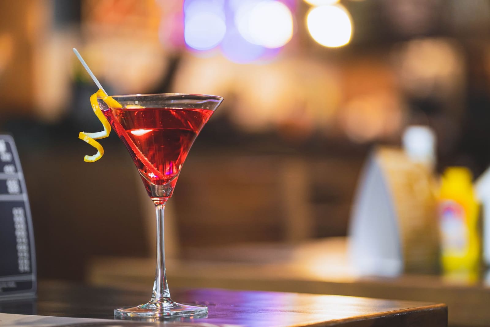Close-up van een sinaasappeltwist boven een bitter aperitief in een glas