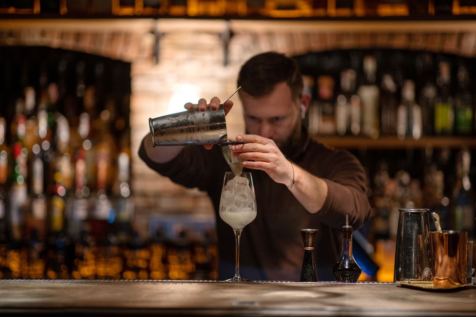 Bartender schenkt een cocktail in aan de bar