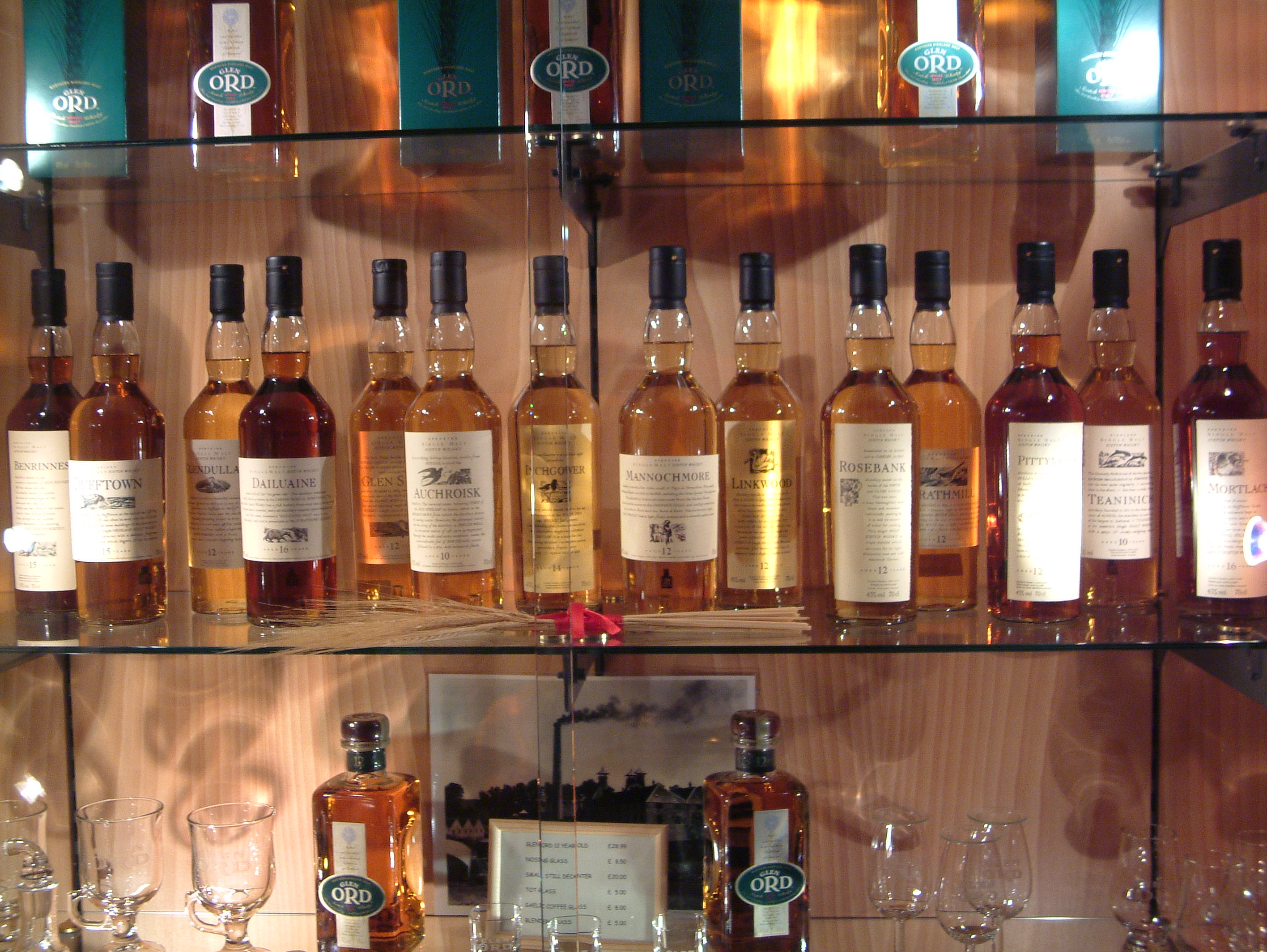 Rij nieuwe whiskyflessen en likeuren op een houten bar, klaar voor proeverij