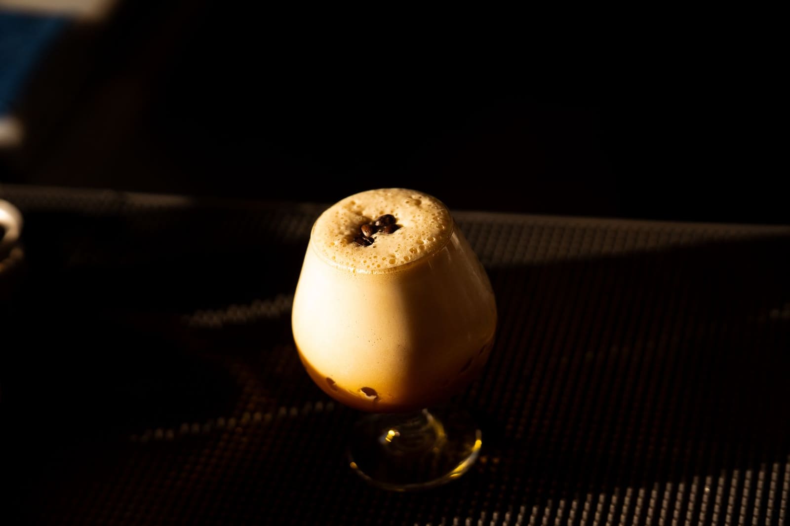 Donkere koffiecocktail geserveerd in een glas met romige schuimlaag