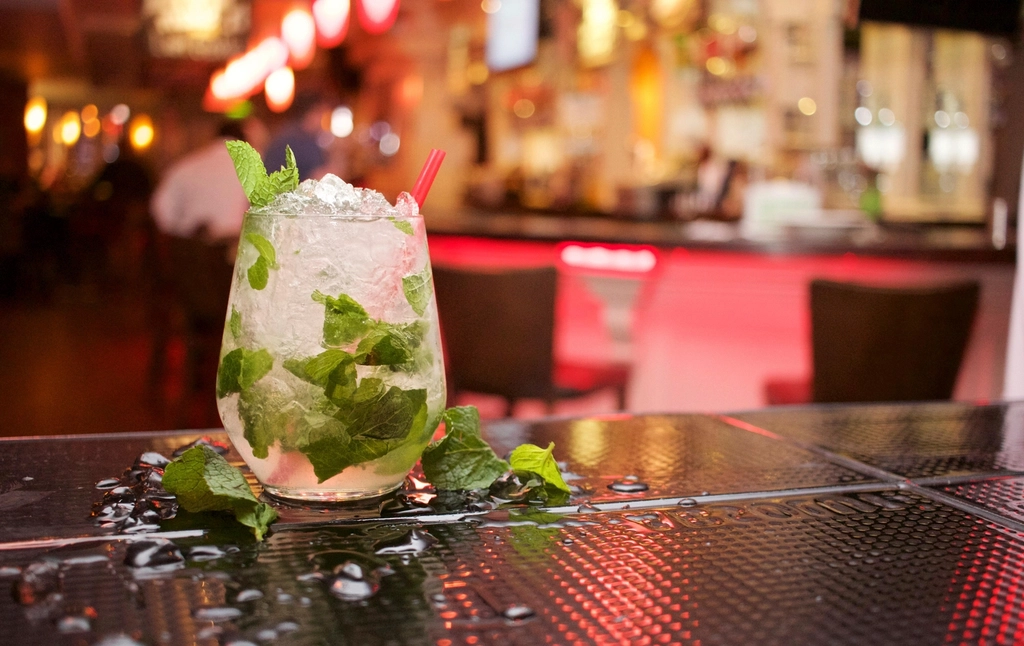 Mojito met verse munt en crushed ice op een bartafel in warm barlicht