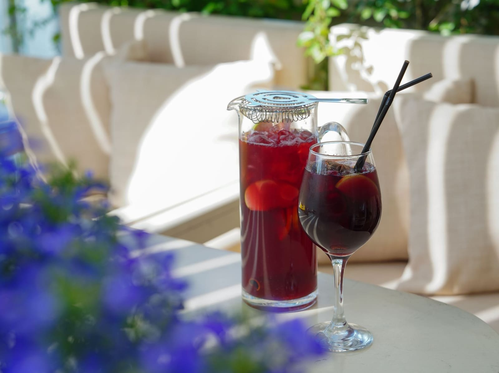 Grote kan alcoholvrije sangria met sinaasappel, appel en kaneelstokjes op een zomerse tafel