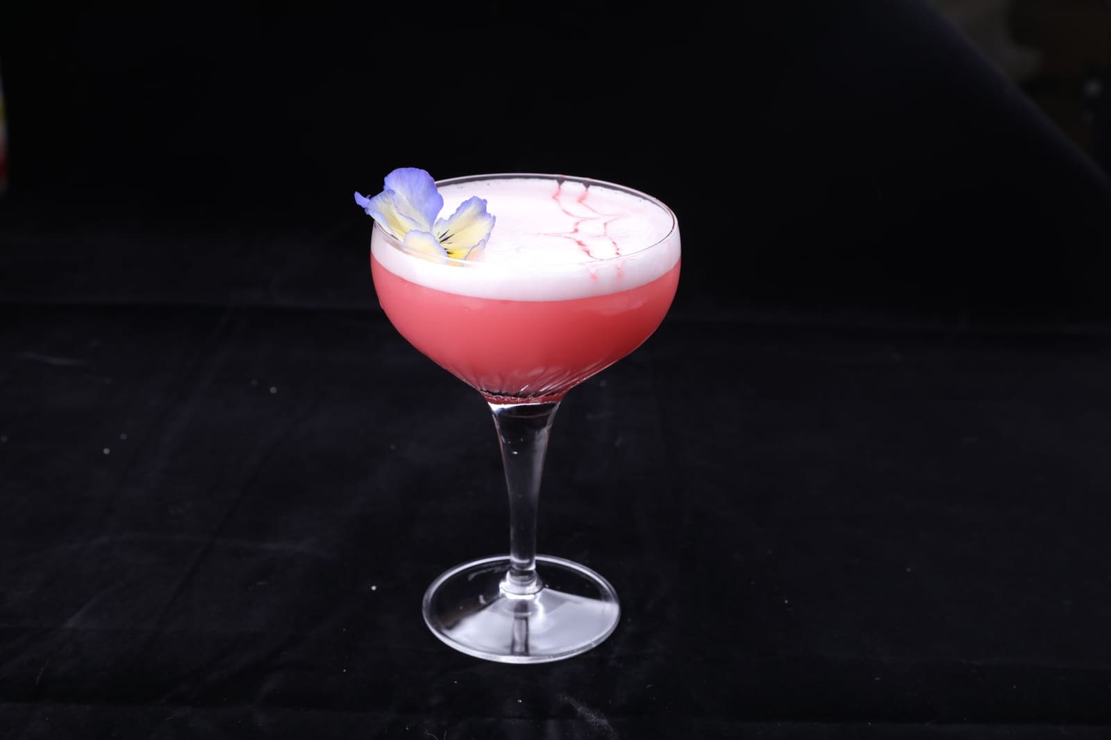 Roze Clover Club cocktail met romig schuim in een coupeglas, gegarneerd met verse frambozen