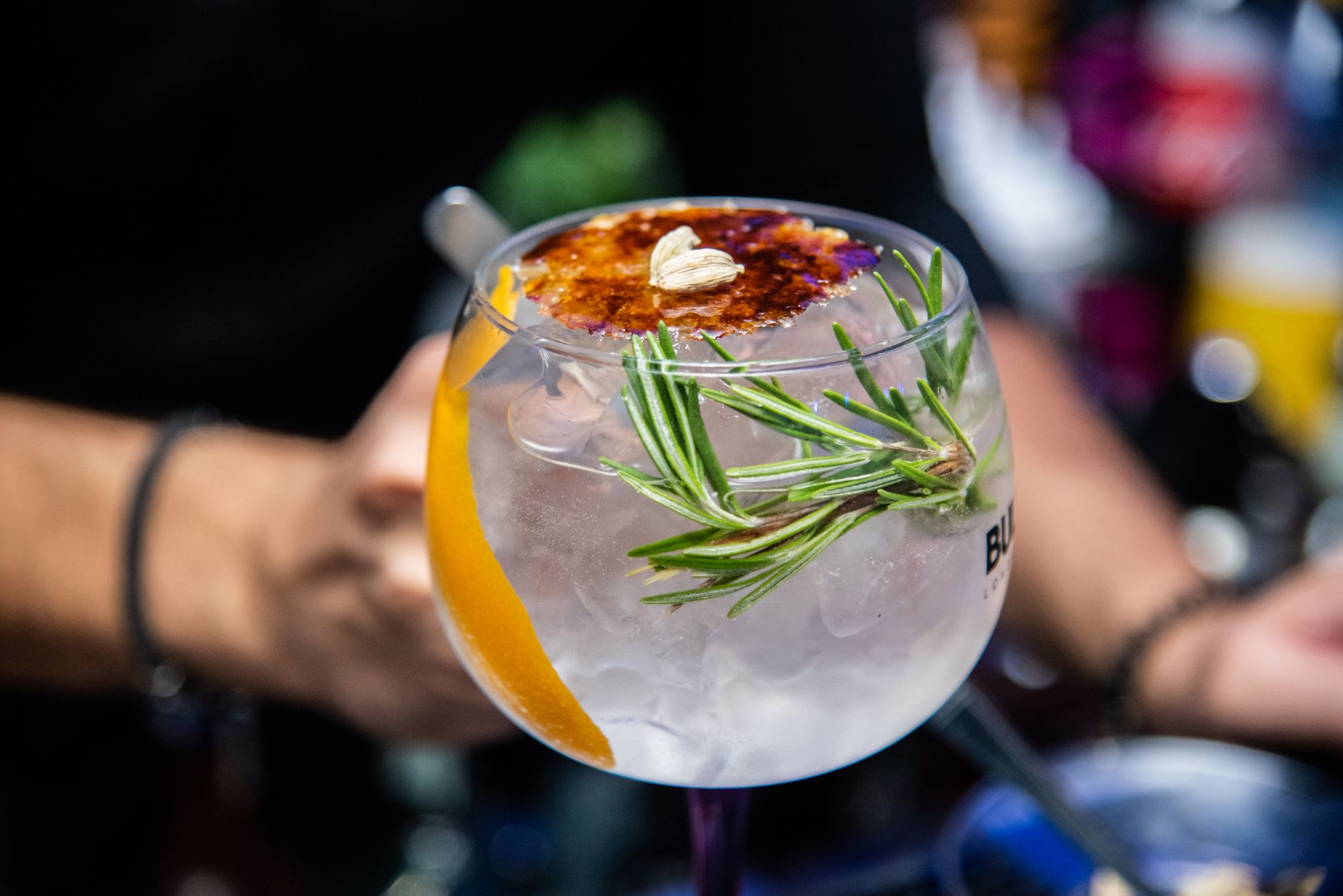 Gin tonic perfect serve in groot wijnglas met ijs en limoengarnering op een bar
