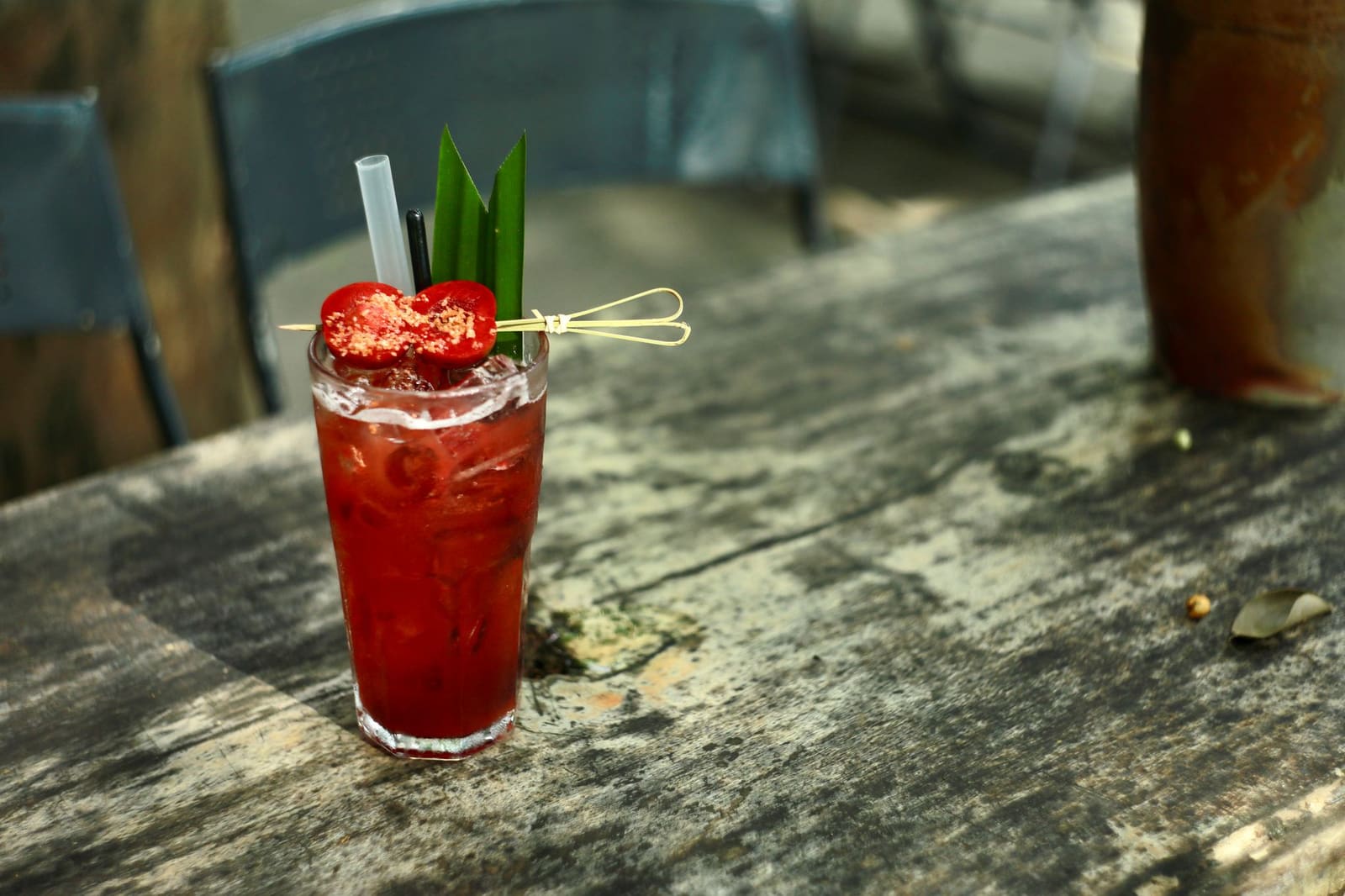 Rode cocktail met ijsblokjes en fruitgarnering in een highball-glas op houten tafel