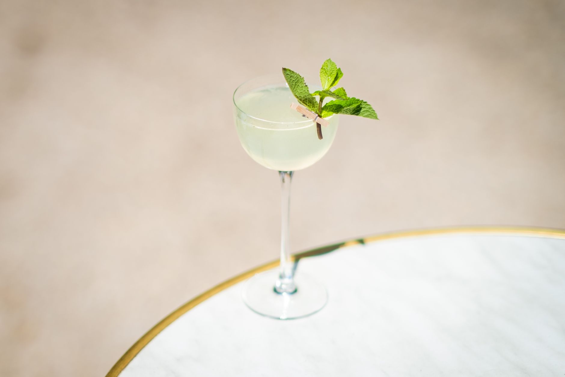Hugo cocktail met prosecco, munt en limoen geserveerd in een groot wijnglas op terras