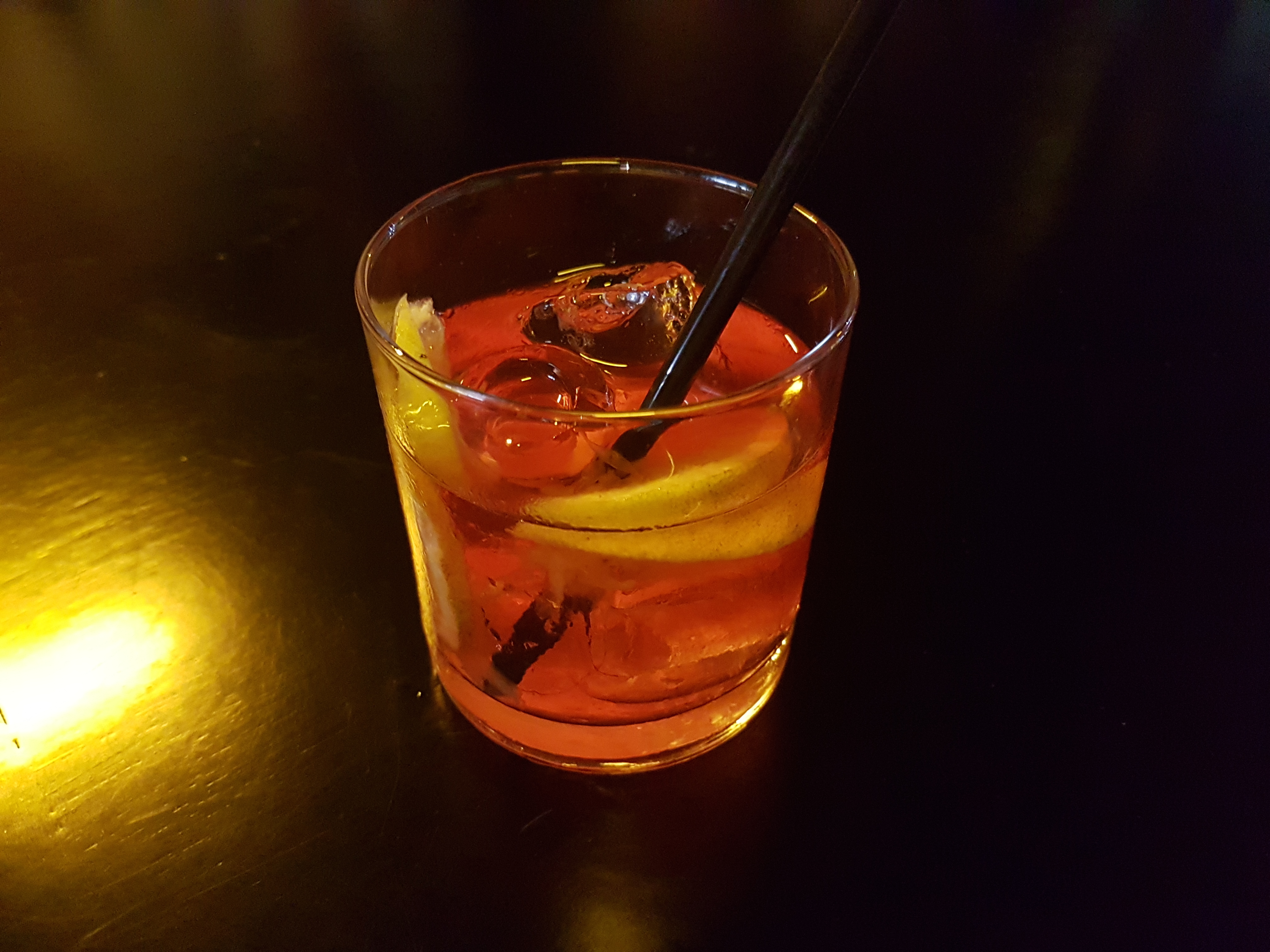 Negroni cocktail in een rocks glas met ijs en een sinaasappelschil als garnering