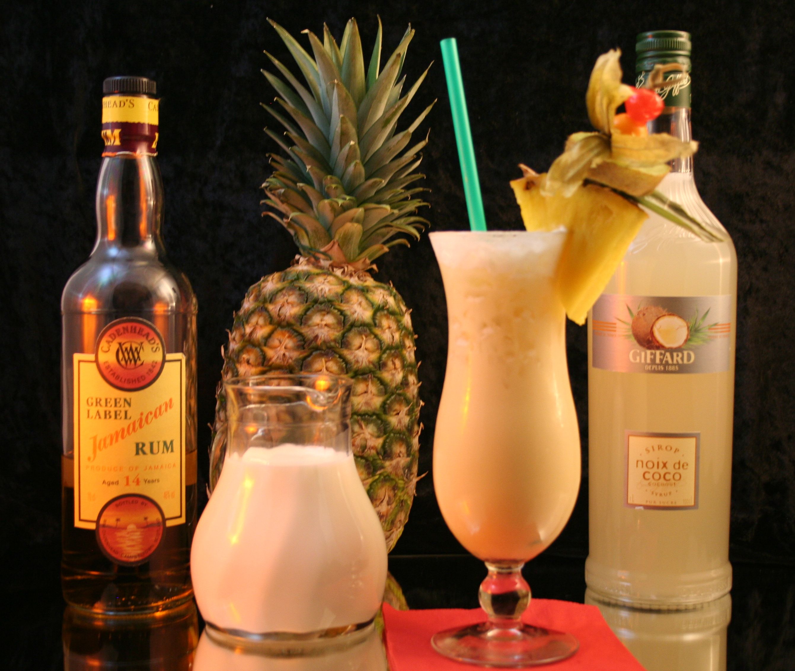 Romige Piña Colada in een highballglas met ananas en kers als garnering