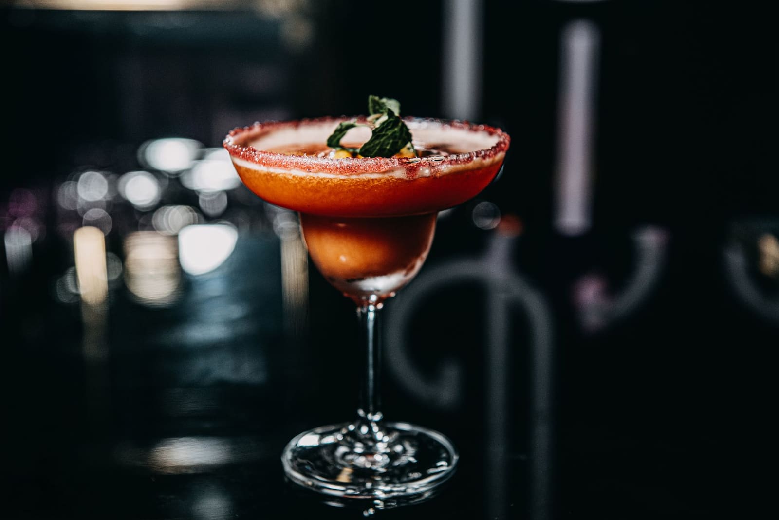 Sidecar cocktail in coupeglas met suikerrand en sinaasappelschil op een bar