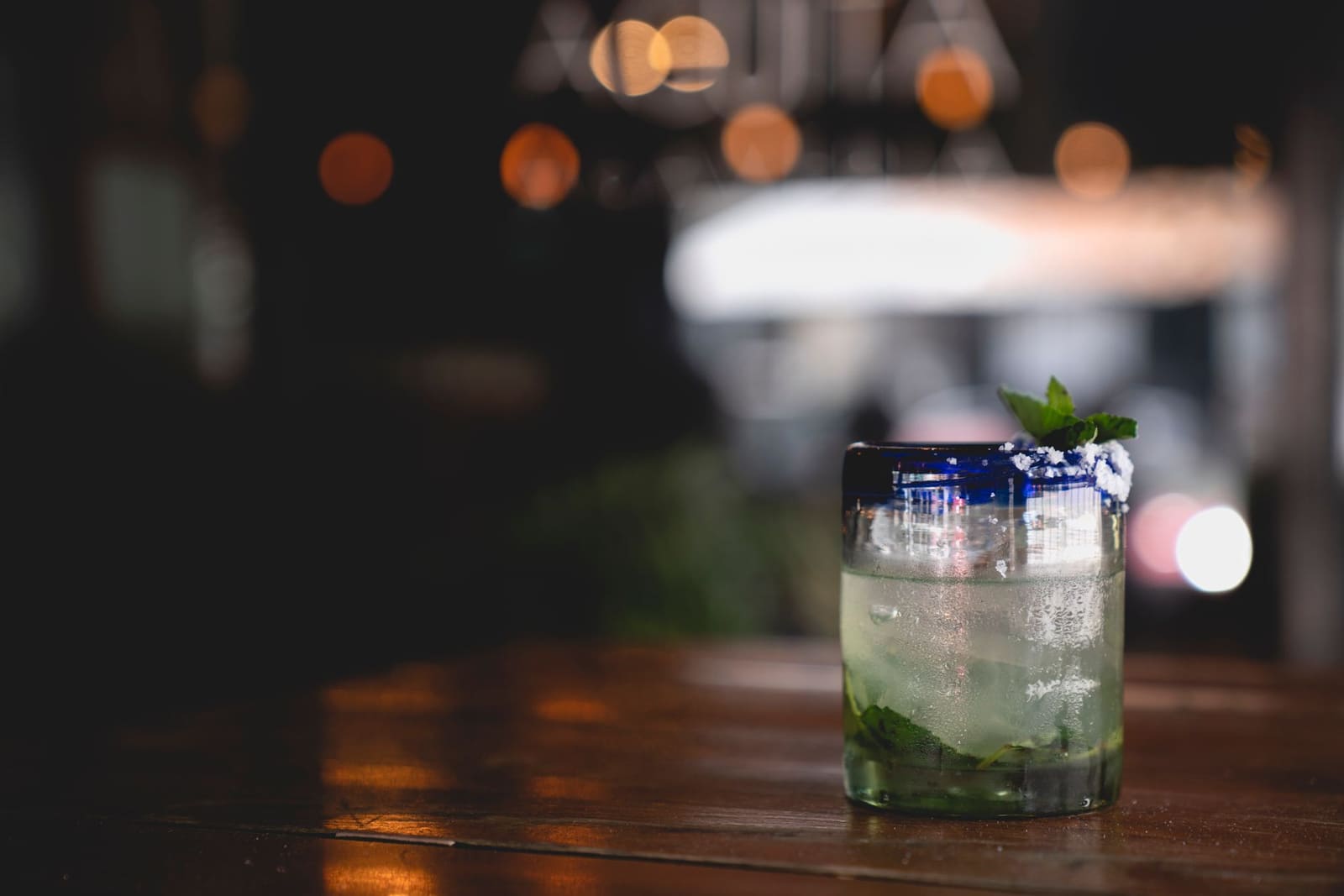 Southside cocktail in coupeglas met muntblaadje, geserveerd op een houten bar