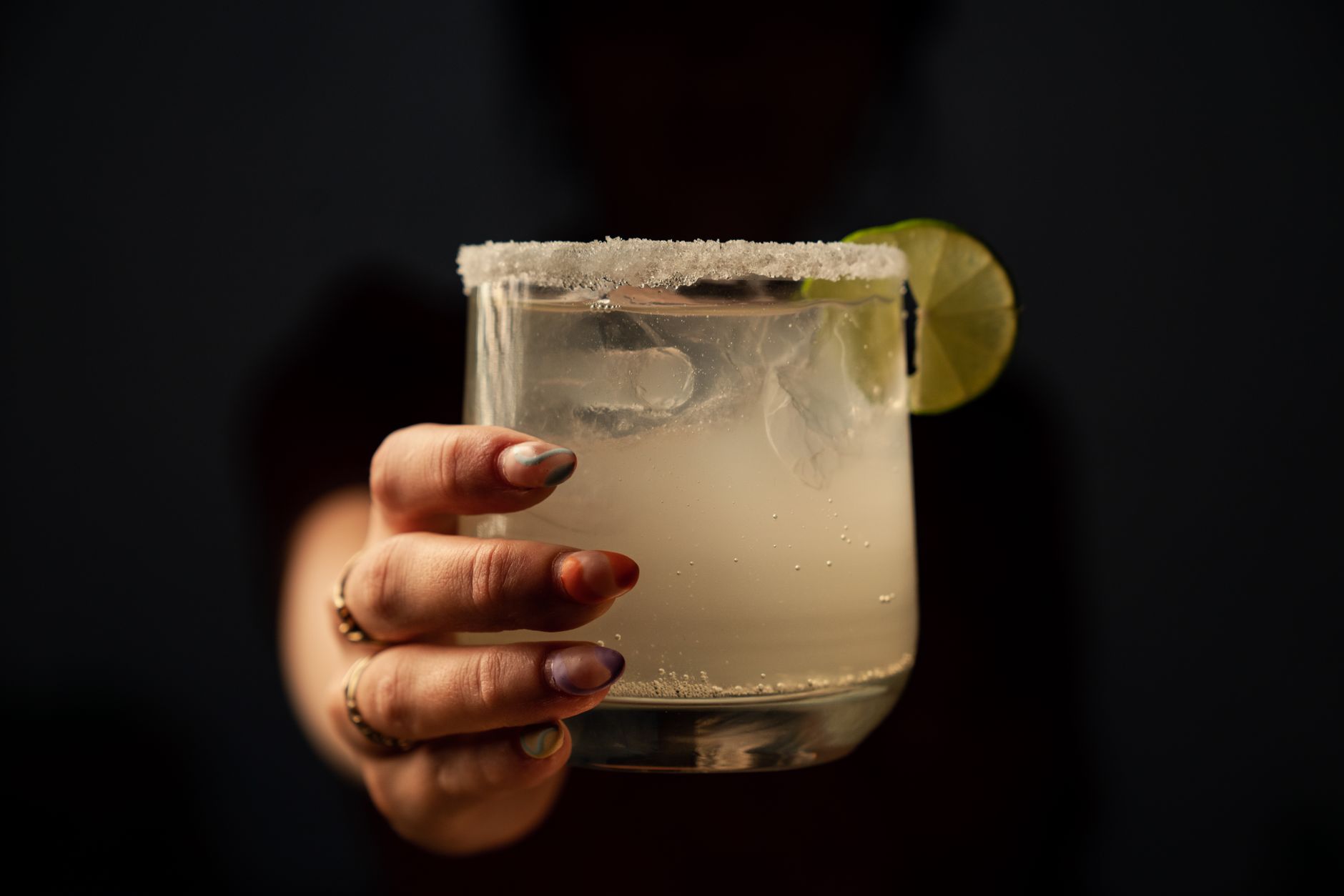 Tommy's Margarita in een rocksglas met ijs, limoenschijfje en zoutrand op een houten bar