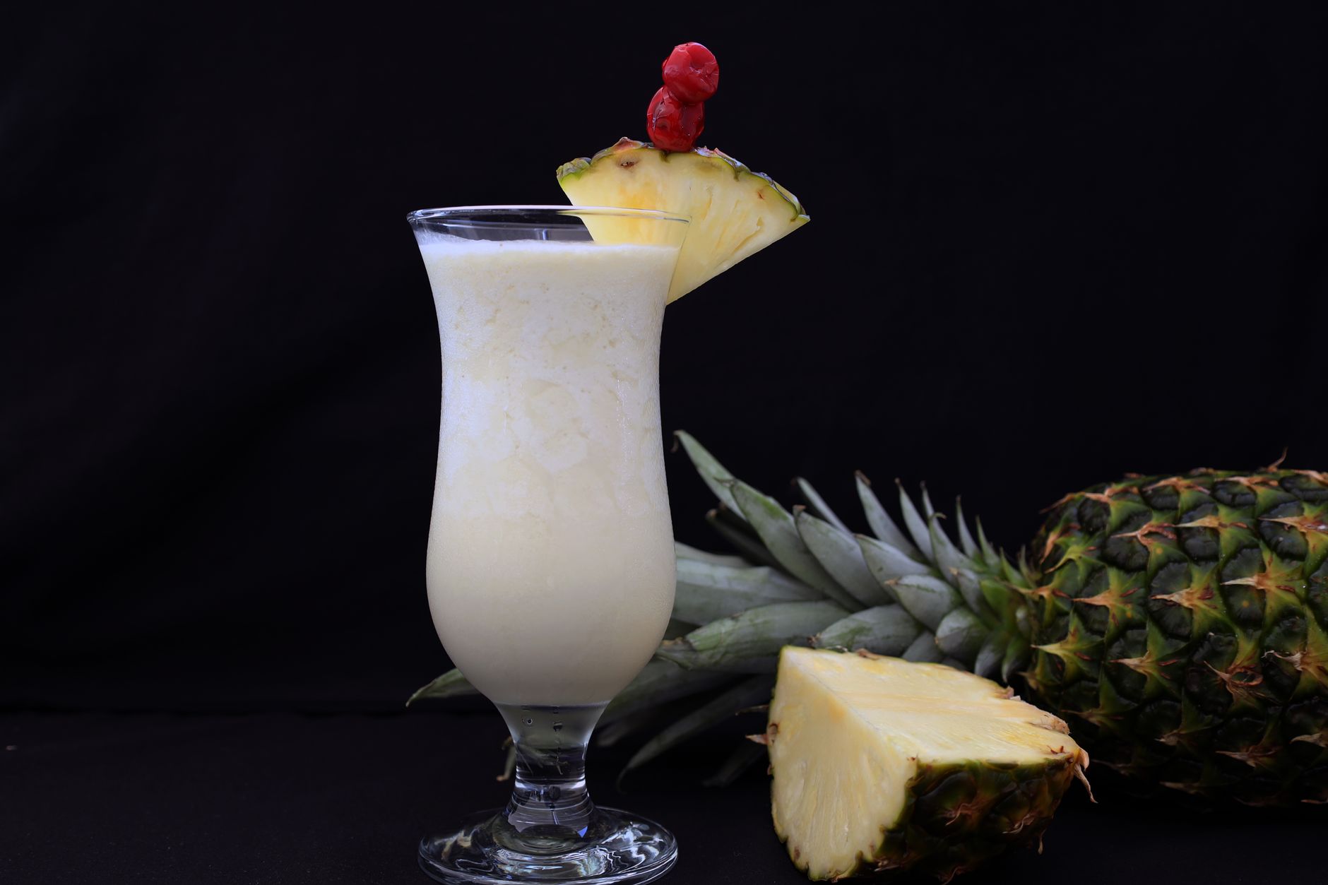 Romige Virgin Pina Colada met ananasplakje en kers in een hoog glas op tafel