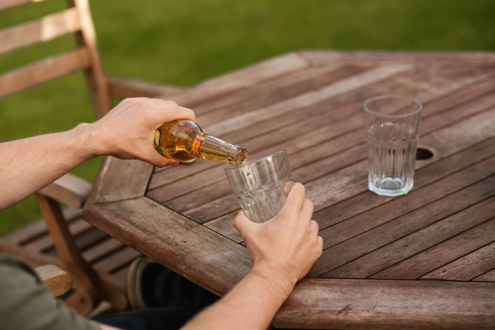 Licht bier wordt gegoten uit een fles in een glas met ijs
