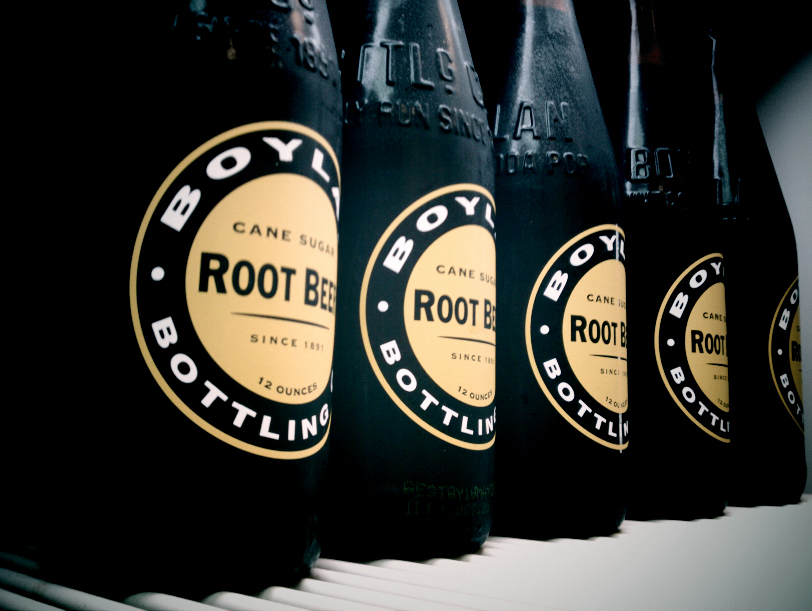 Verschillende flessen root beer naast een glas met ijs, klaar voor een root beer float
