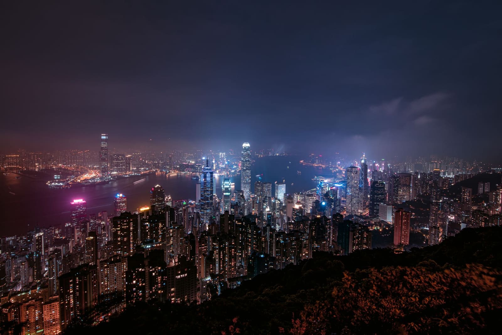 Skyline van Hong Kong bij nacht met verlichte wolkenkrabbers langs de haven